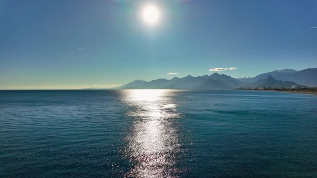 Panoramic view of antalya bay with sparkling mediterranean sea sun glare and taurus mountains backdrop.