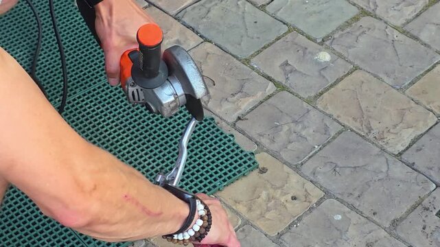 Man using angle grinder to cut metal rod outdoors. Craftsman performing metalwork task. Construction worker professional tool operation for hardware renovation job.