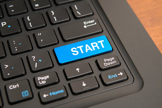 Close up of a computer keyboard with a blue start key, representing new beginnings, business launch, project initiation, motivation, opportunity, and goal achievement concepts.