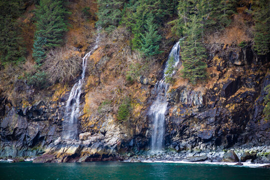 Kenai Fjords National Park, dual waterfalls on tree covered cliffside, horizontal