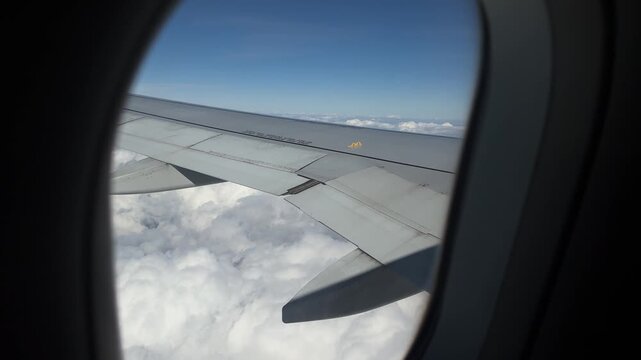 First-person view: a passenger gazes through the airplane window, soaring high above the clouds, revealing a peaceful, endless sky and serene atmosphere.