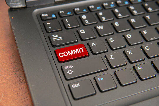 Close up of a computer keyboard with a red commit key, representing commitment, dedication, goal achievement, business execution, personal responsibility, and long-term success concepts.