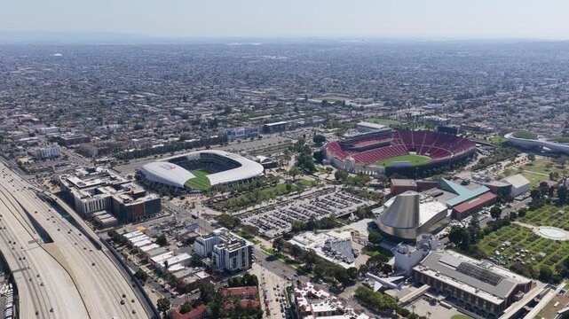 Aerial survey of Los Angeles showing BMO Stadium and Memorial Coliseum in Exposition Park with Harbor Freeway traffic flowing through University Park cityscape