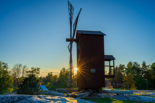 Golden sunset over historical wooden windmill with dramatic sunstar
