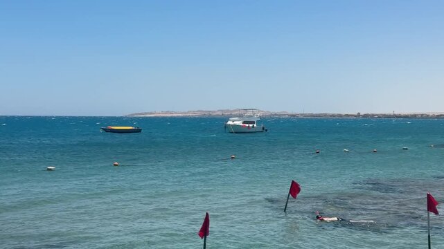 Hotel beachfront on Red Sea with swimming buoys and safety rope, calm turquoise water, sunny resort.