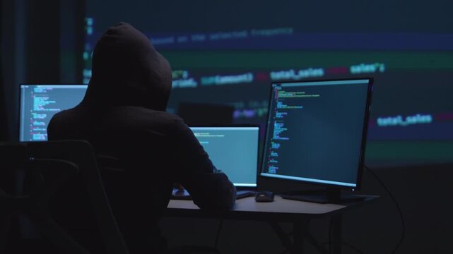 Focused Hacker Programming with Multiple Screens Displaying Code and Cybersecurity Tools