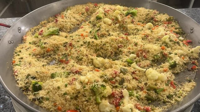 Vegetarian paella with rice and vegetables in a large restaurant frying pan. Colorful, aromatic, delicious, freshly made.