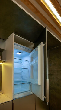 Modern kitchen with an open refrigerator and integrated wooden ceiling details
