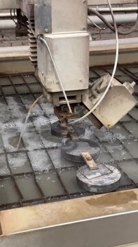 Thick aluminum plate sliced by waterjet cutter with high-pressure abrasive stream, creating precise clean edges without heat distortion.