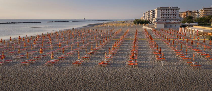 Aerial shot of sandy beach with umbrellas and gazebos.Summer vacation concept.Lido Adriano town,Adriatic coast, Emilia Romagna,Italy.
