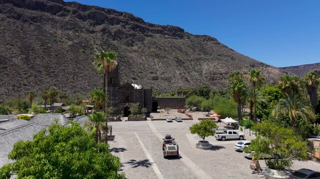 Aerial views show an SUV with a teardrop camper visiting San Javier Mission near Loreto in Baja California Sur.