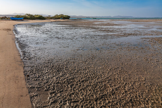 Beautiful tropical lagoon at low tide with a small wooden fishing boat on the shore in Marsa Alam region, Red Sea coast.
