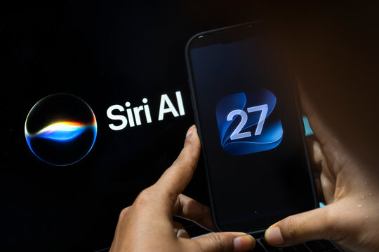 In this photo illustration, a person holds an iPhone displaying the iOS 27 logo beside a screen showing Siri AI branding on June 10, 2026, in New Delhi, India.