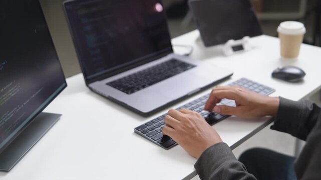 Focused Software Developer Working Remotely on Laptop with Multiple Screens for Coding Tasks
