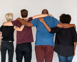Naklejka premium Diverse group of four friends standing arm in arm, seen from behind