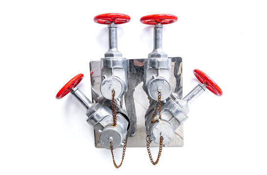 Industrial fire department connection with red valve wheels on a metal plate isolated on white background