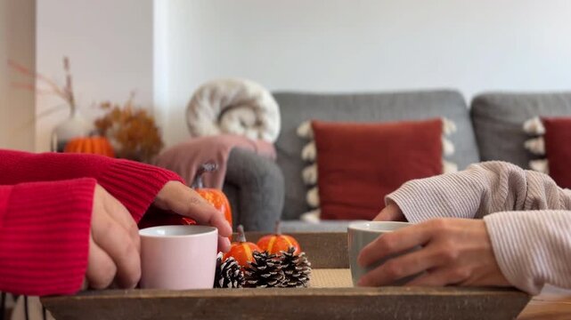 Manos de pareja cogiendo tazas con decoraci&oacute;n oto&ntilde;al