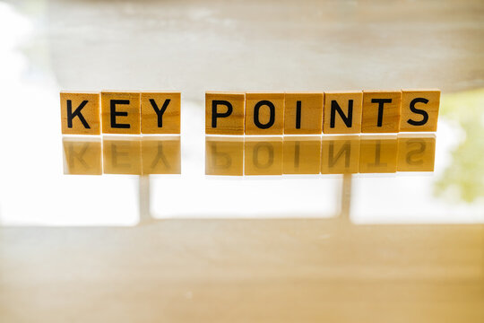 Wooden tiles with the letters of Key Points printed on with a reflection on the surface below, used for summarising a subject