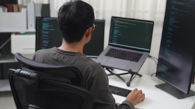 Focused Developer Working on Multiple Screens in a Workspace Environment