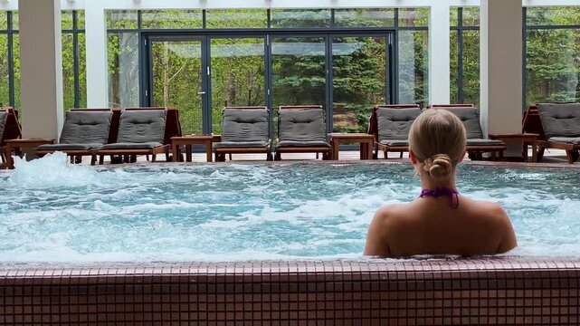 4K SPA vertical video footage of blonde woman relaxing in jacuzzi hot tub, luxury wellness spa, serene wellness lifestyle, beauty relaxation, indoor spa atmosphere.