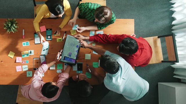 Top view of skilled software developer working together to develop Ux Ui design for mobile phone interface. Programmer sharing develop plan while looking at wireframe prototype icon. Convocation.