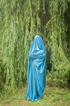 abstract fine art portrait of anonymous veiled blue silhouette near green willow