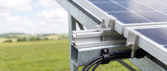 Naklejka premium Close-up of solar panel mounting and cables on ground-mounted solar array in countryside