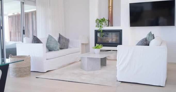 At start, camera is panning forward, framing sofa, chair, table in living room and showing space