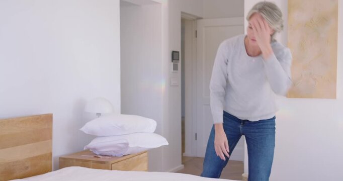 Diverse couple making bed in bedroom woman shaking duvet man helping smoothing placing pillows