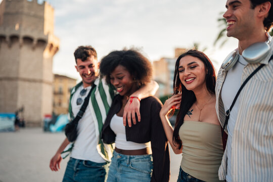 Diverse group of young friends walking happily together through a city street during golden hour in valencia
