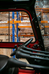 View of logistics warehouse pallet racking seen through the cab side window of a forklift. The scene captures the operator’s perspective within an industrial storage environment, featuring pallets © Val