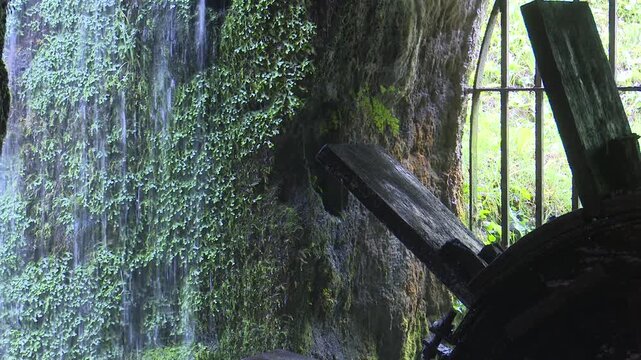 Moss covered waterfall and old water wheel mechanism a section of a flowing