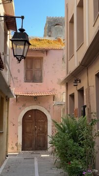 Narrow alley in the old town of Rethymno, Crete, with traditional pastel buildings, wooden doors, vintage street lamp and Mediterranean architecture on a sunny day. Vertical video.