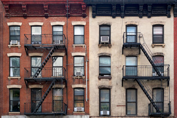 Exterior view of a classic apartment building facade in midtown New York with symmetrical rows of windows, brick masonry, and traditional exterior emergency stairs. © Jose Luis Stephens