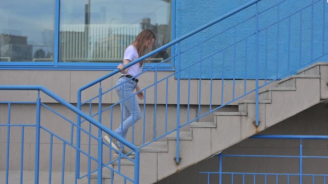 A Caucasian woman with mild cerebral palsy climbs stairs