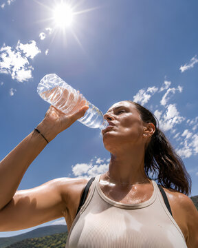 Hydratation importante pendant une canicule avec une femme buvant de l&rsquo;eau au soleil.