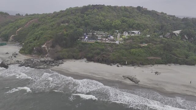 Aerial view of a coastal cliff near Dream Beach in Chapora, Goa, overlooking the Chapora River and the Arabian Sea, showcasing rugged terrain, lush vegetation, and scenic tropical landscapes.