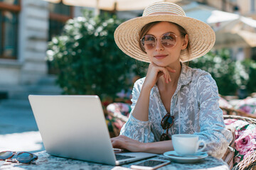 Fototapeta premium Confident freelancer enjoys sunny day while working on laptop at outdoor cafe