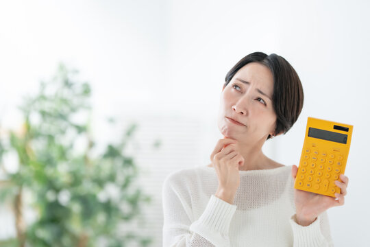 電卓を持って悩む女性