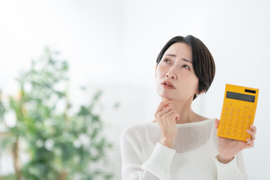 電卓を持って悩む女性