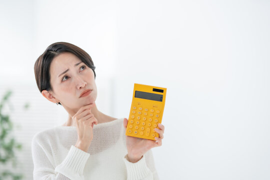 電卓を持って悩む女性