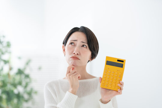 電卓を持って悩む女性