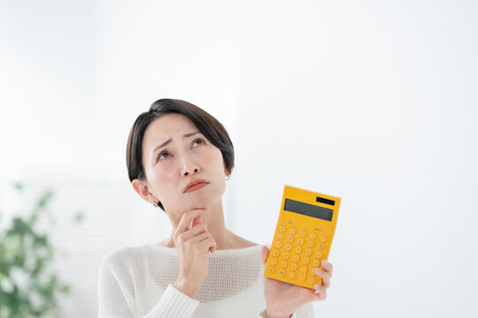 電卓を持って悩む女性