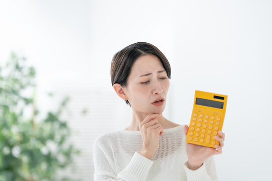 電卓を持って悩む女性