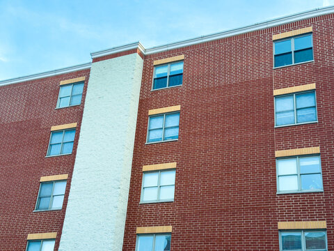 Building with red brick exterior and several windows on a clear day in the afternoon, showing a simple urban setting
