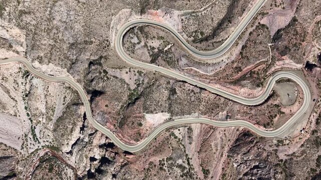 Top-down aerial shot of a winding mountain road forming a zigzag pattern.