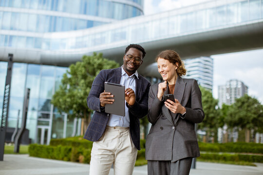 Two people share information outside a modern office building in the city