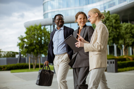 Business people walking outside office building in city during afternoon