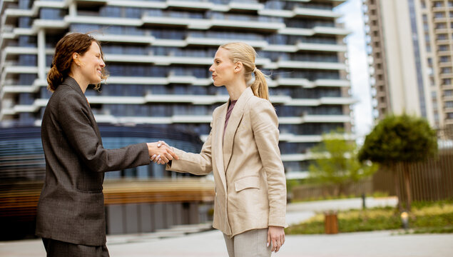 Two business people shake hands in a modern office area during the day