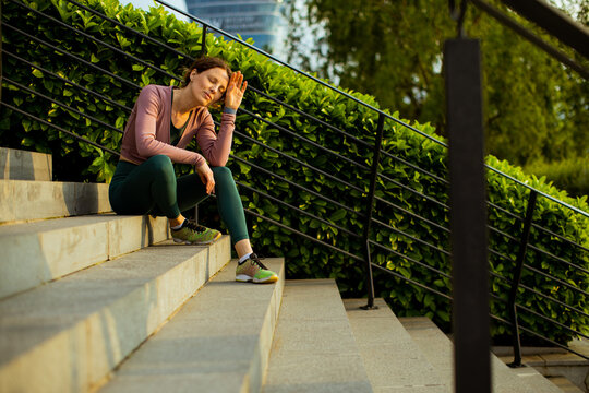 Woman resting on steps in a park during late afternoon